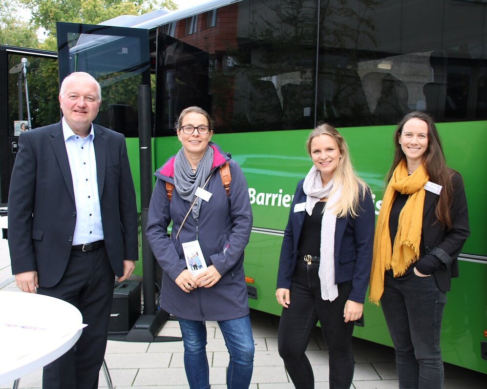 Der Landrat Dr. Henning Görtz steht mit Mitgliedern der Lokalen Allianz vor einem grünen Bus