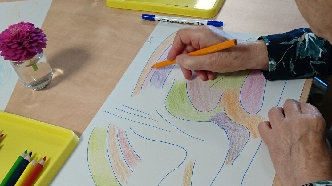 Auf dem Foto sieht man eine ältere Dame, die ein abstraktes Bild malt