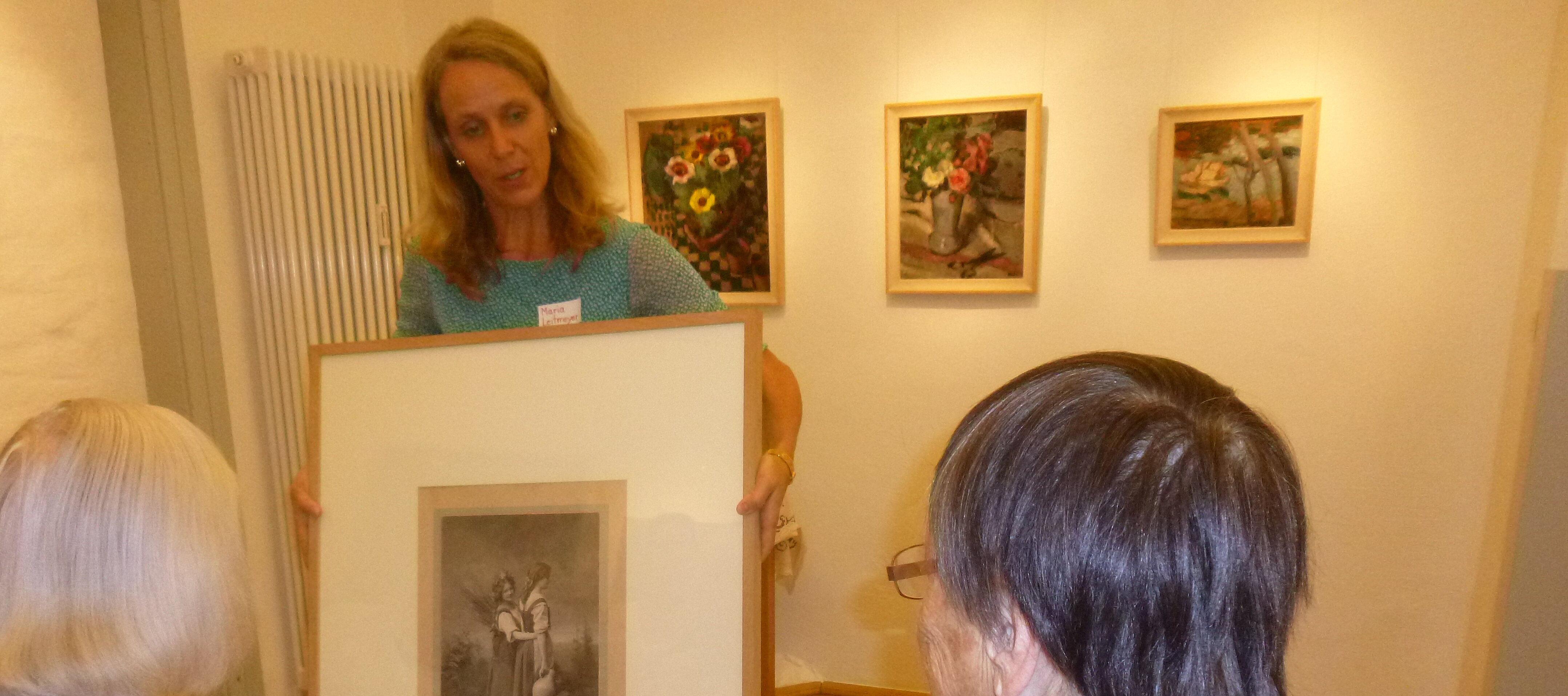 Foto: Eine Frau zeigt zwei älteren Damen ein Kunstwerk