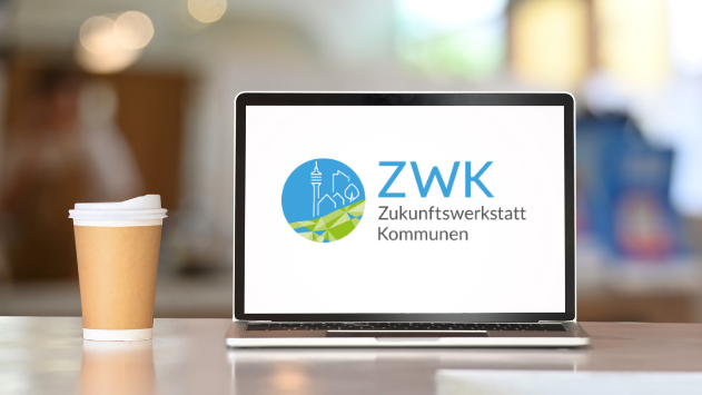 Aufgeklapptes Laptop: Auf dem Bildschirm ist das Logo der Zukunftswerkstatt Kommunen