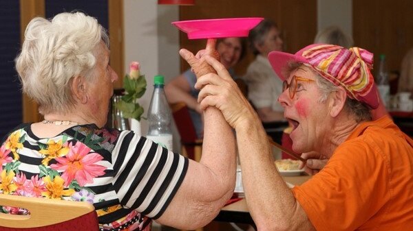 Der Clown Penny Pensky besucht Bewohnerinnen und Bewohner des Stiftungsdorfs Hollergrund Foto: Zwei sitzende ältere Damen mit einem Jonglierteller.