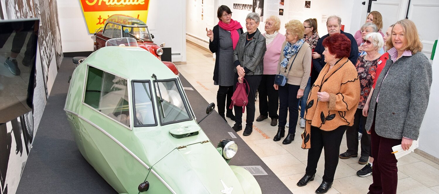 Foto: Eine Gruppe von Seniorinnen und Senioren betrachtet in der Städtischen Galerie Rosenheim einen lindgrünen Oldtimer