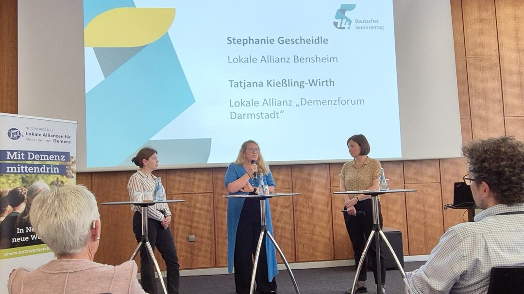 An drei Stehtischen stehen Stephanie Gescheidle (Lokale Allianz Bensheim), Tatjana Kießling-Wirth (Lokale Allianz "Demenzforum Darmstadt") und die Moderatorin Dr. Katja Hilser 