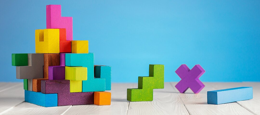 © Radachynskyi Dreidimensionales Gebilde von ineinander greifenden, bunten Bausteinen. Ein paar weitere Bausteine liegen daneben.