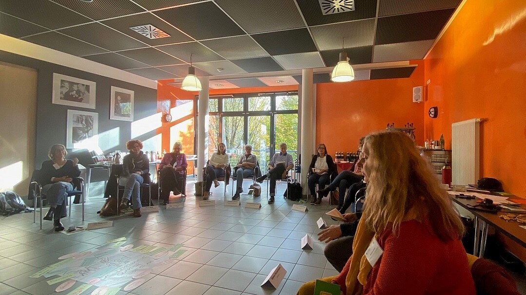 Die Teilnehmenden sitzen in einem Halbkreis