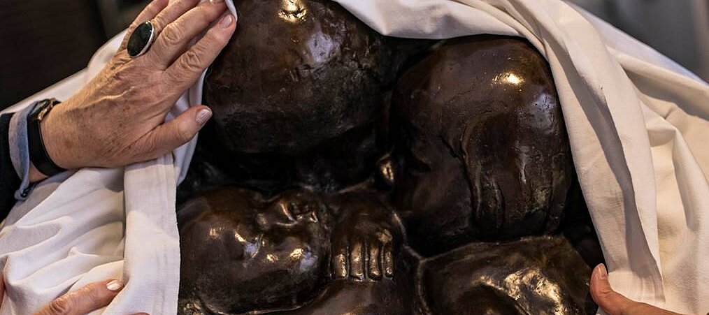{Sinnlicher Zugang zur Kunst: Die Skulptur „Mutter mit zwei Kindern“ von Käthe Kollwitz darf ertastet werden Auf dem Foto sieht man eine Skulptur von Käthe Kollwitz, die von zwei Personen mit den Händen ertastet wird
