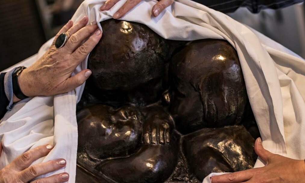 uf dem Foto sieht man eine Skulptur von Käthe Kollwitz, die von zwei Personen mit den Händen ertastet wird