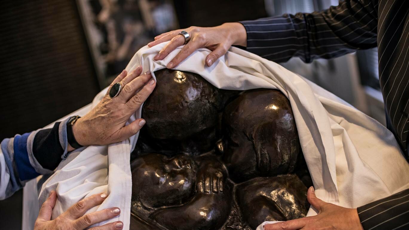 Auf dem Foto sieht man eine Skulptur von Käthe Kollwitz, die von zwei Personen mit den Händen ertastet wird