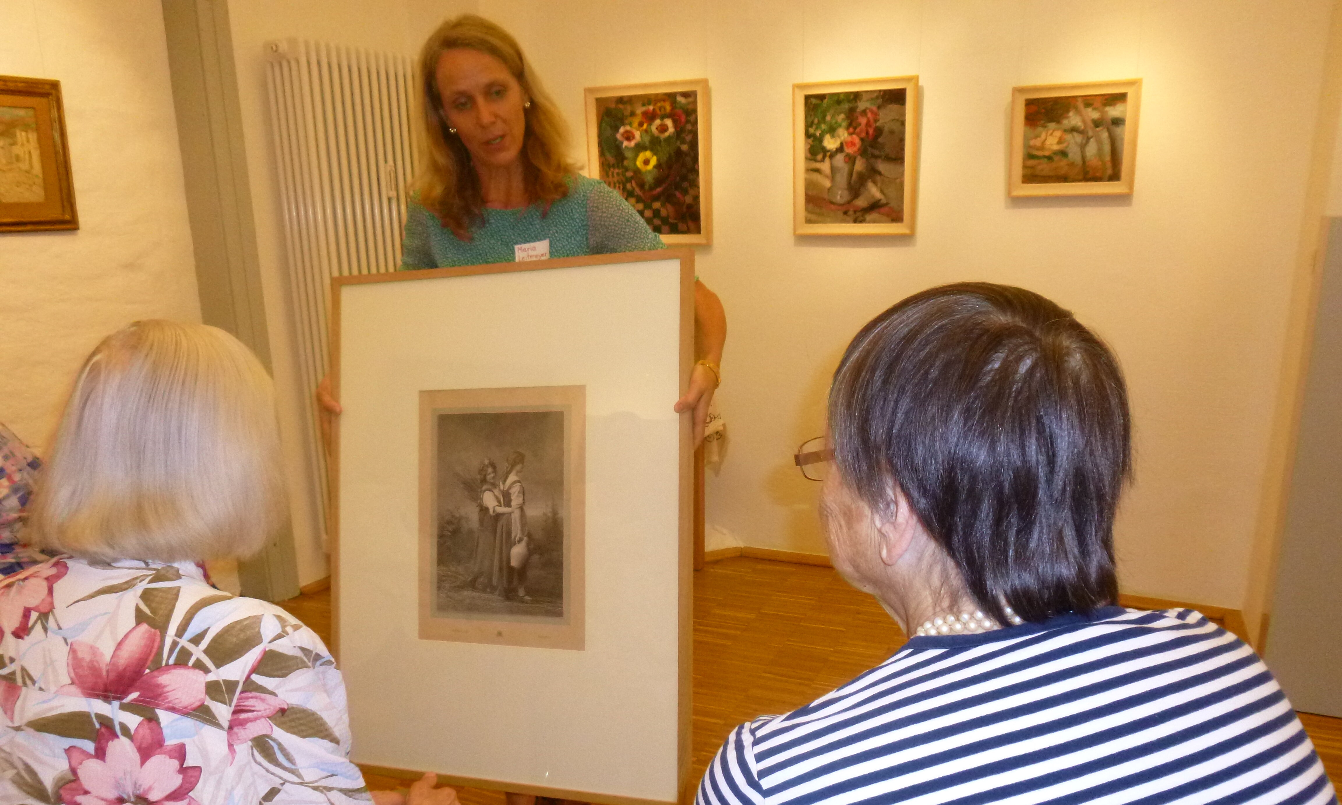 Eine Frau zeigt zwei älteren Damen ein Kunstwerk