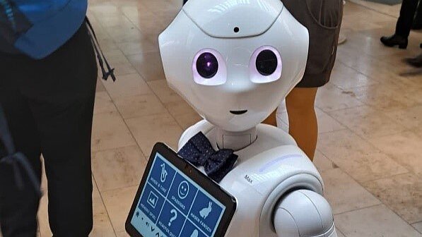 Roboter „Emma“, entwickelt von Hannes Eilers, Laboringenieur für Robotik, Fachhochschule Kiel | „Demenz-Fachtag“, Oktober 2023 in Syke Foto: Weißer Roboter mit großen schwarzen Augen, schwarzer Fliege und Touchscreen vor der Brust.