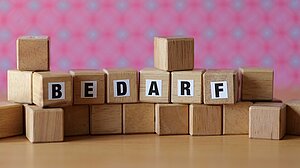 Holzklötzchen mit Buchstaben, die den Begriff "Bedarf" bilden