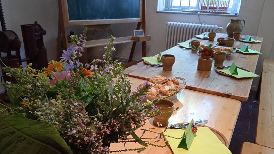 Gedeckte Kaffeetafel mit Kuchen und einem Strauß Blumen