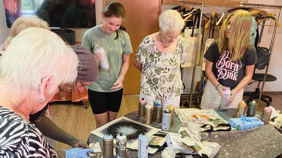 Foto: Seniorinnen und Schülerinnen stehen um einen Tisch mit Bastelmaterial