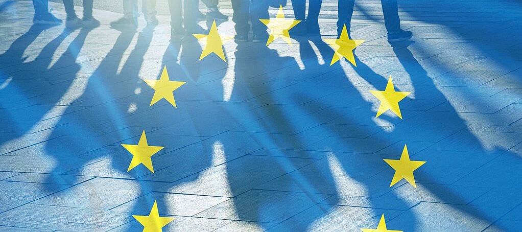 Durchscheinende Europaflagge mit Schattenumrissen von Menschen 