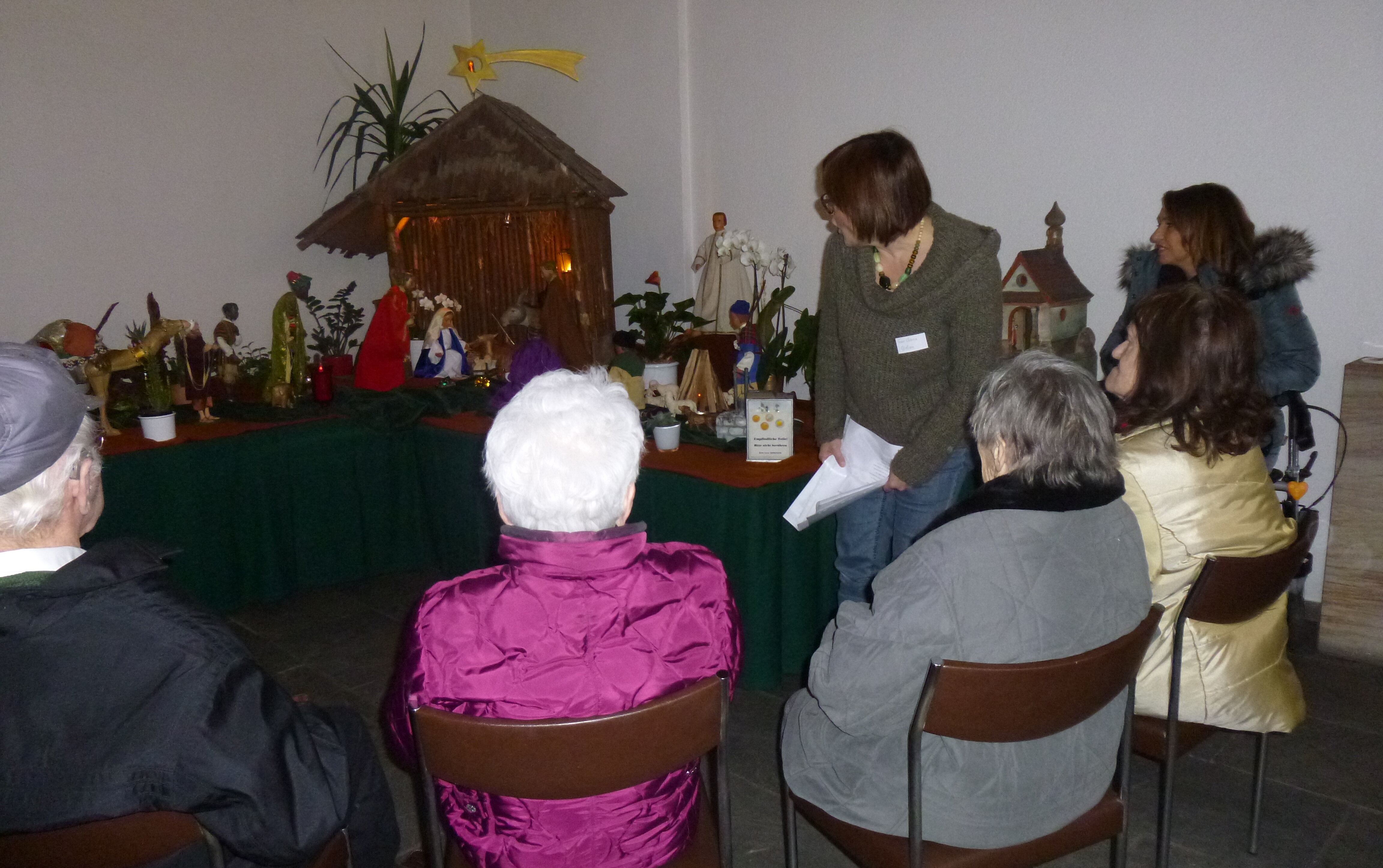 Mehrere Personen betrachten eine Weihnachtskrippe 