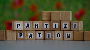 Holzklötzchen mit Buchstaben, die den Begriff "Partizipation" bilden