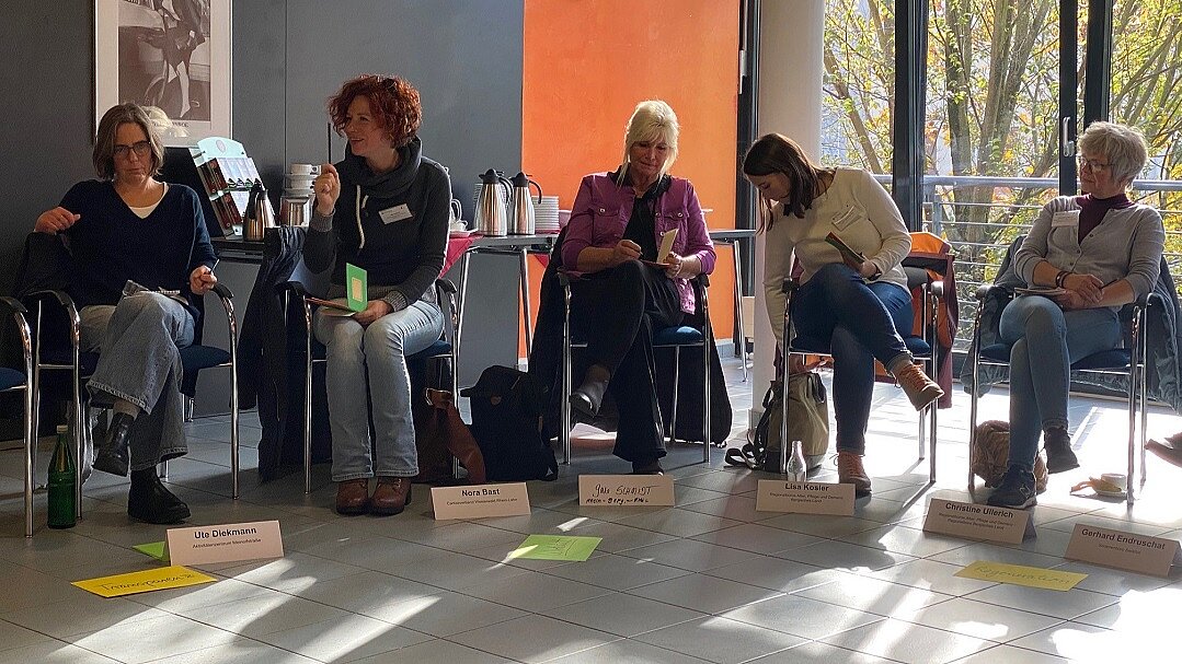 Die Teilnehmenden sitzen in einem Halbkreis