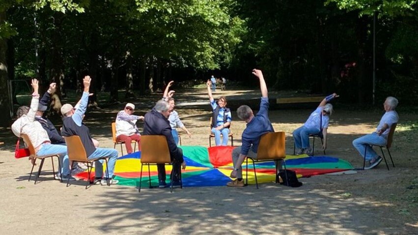 Foto: Senior*innen machen Gymnastik im Sitzen in einem Park