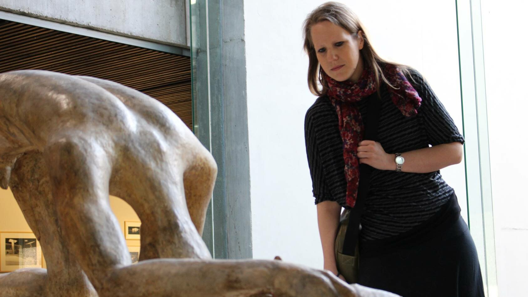 Auf diesem Foto sieht man eine Skulptur und eine Frau, die das Werk betrachtet