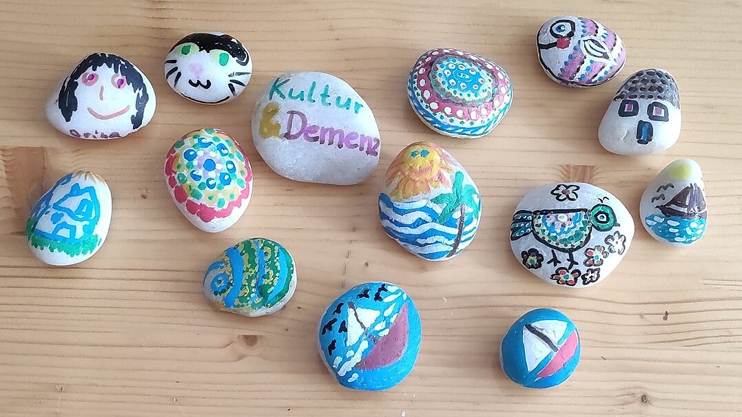 Foto: Vogelperspektive: Bunt bemalte Steine, die auf einem Tisch liegen