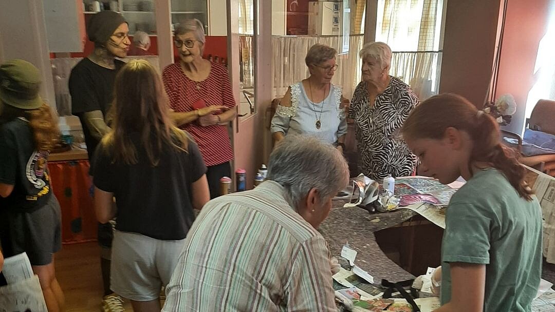 Foto: Seniorinnen und Schülerinnen stehen um einen Tisch mit Bastelmaterial