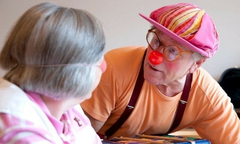 Ein Mann verkleidet als Clown und eine ältere Dame.