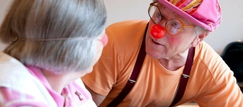 Ein Mann verkleidet als Clown und eine ältere Dame.