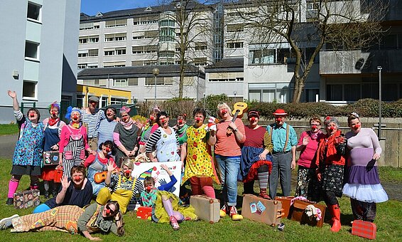 Die ehrenamtlichen „Gerontoclowns“ freuen sich auf ihre Besuche bei den teilweise von Demenz betroffenen Bewohnerinnen und Bewohnern im Krankenhaus und Altenheim | © Stadtmarketing Stadtbüro Kirchen Gruppenbild von Frauen und Männern auf einer Wiese. Alle sind als Clowns verkleidet.