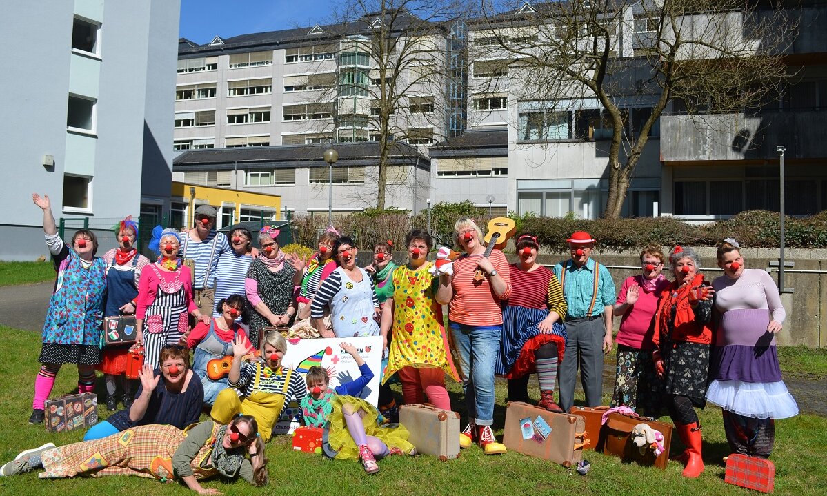 Gruppenbild von Frauen und Männern auf einer Wiese. Alle sind als Clowns verkleidet. 