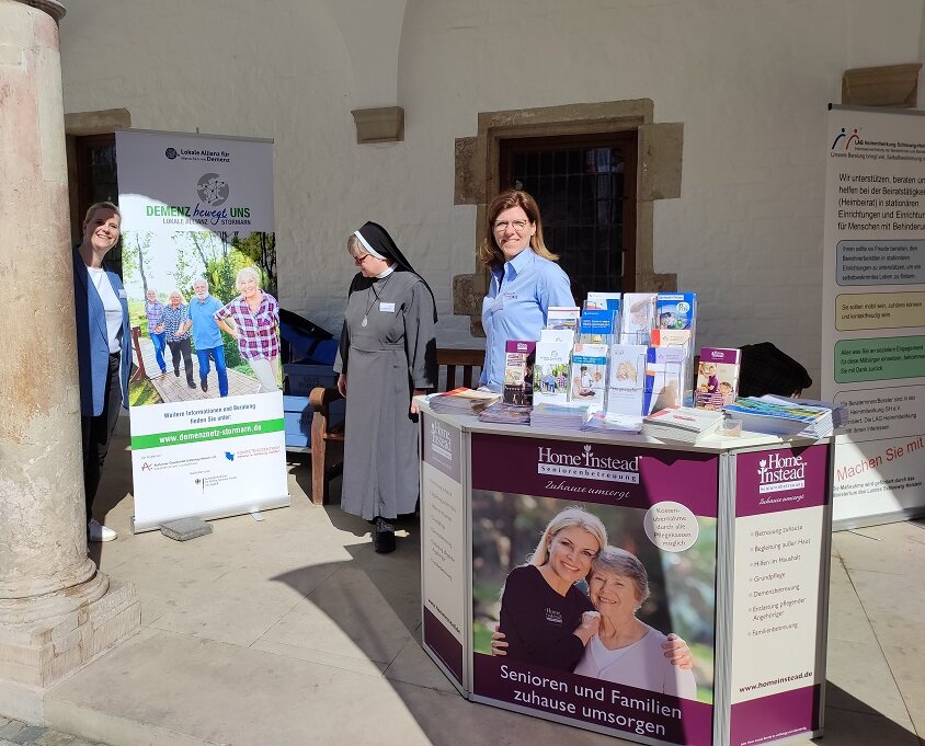 Messestand der Lokalen Allianz mit neuem Roll-Up auf dem überdachten Vorplatz einer Kirche