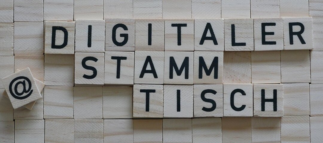 Der Begriff "Digitaler Stammtisch" gelegt aus Holzplättchen mit schwarzen Buchstaben