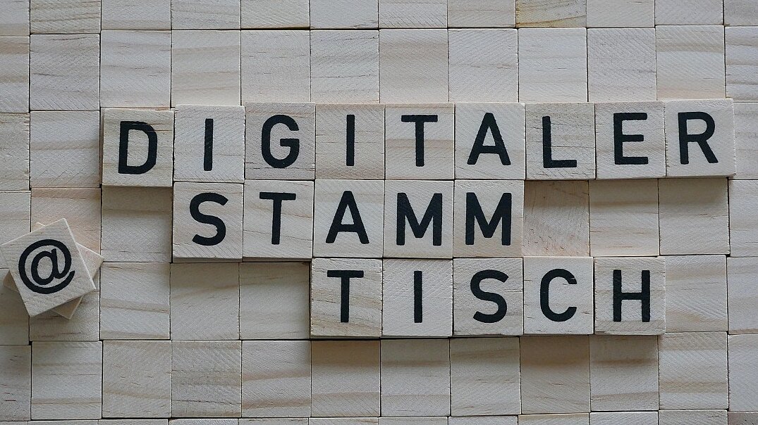 Der Begriff "Digitaler Stammtisch" gelegt aus Holzplättchen mit schwarzen Buchstaben