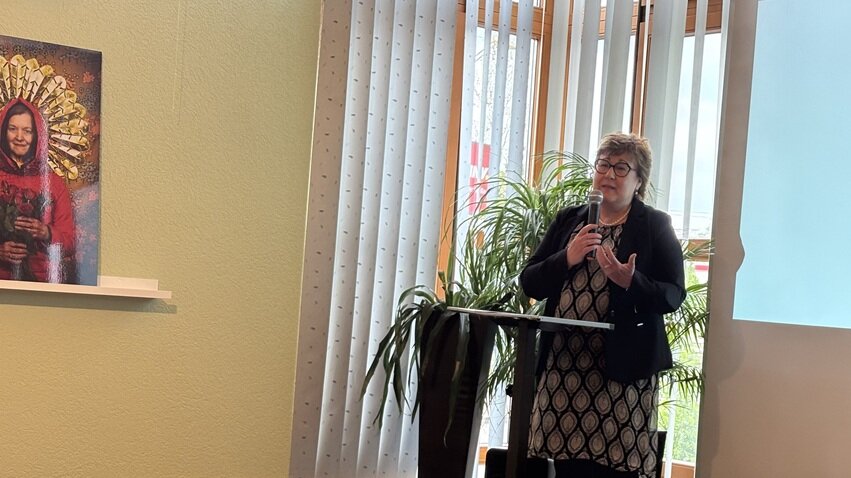 Auftaktveranstaltung am 25. April 2025: Petra Grimm-Benne, Ministerin für Arbeit, Soziales, Gesundheit und Gleichstellung begrüßt die Anwesenden. Foto: Petra Grimm-Benne hält Rede an Rednerpult auf einer Bühne eines Veranstaltungsraums vor einer Leinwand stehend.