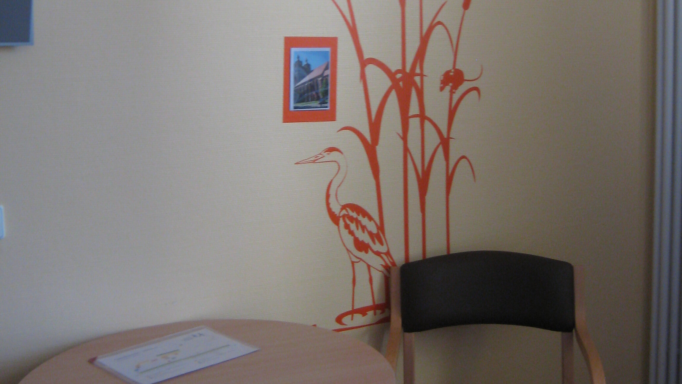Blick in ein Patientenzimmer, dessen Wand durch eine Wandillustration und Fotos optisch gestaltet ist