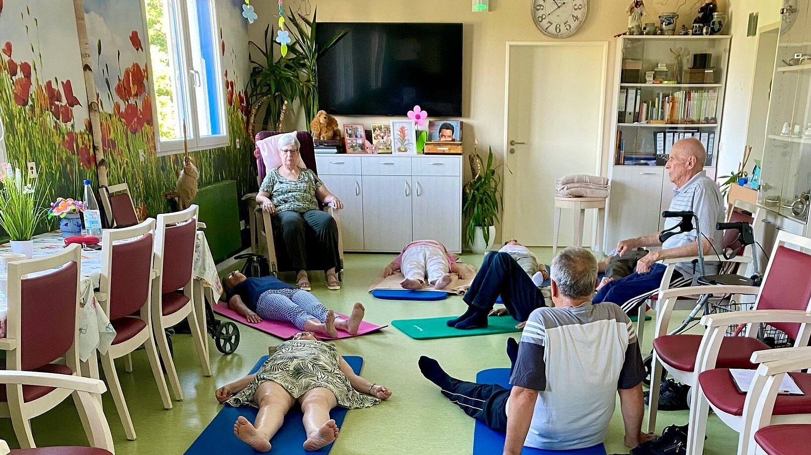 Foto: Mehrere Menschen liegen mit geschlossenen Augen auf farbigen Fitnessmatten.