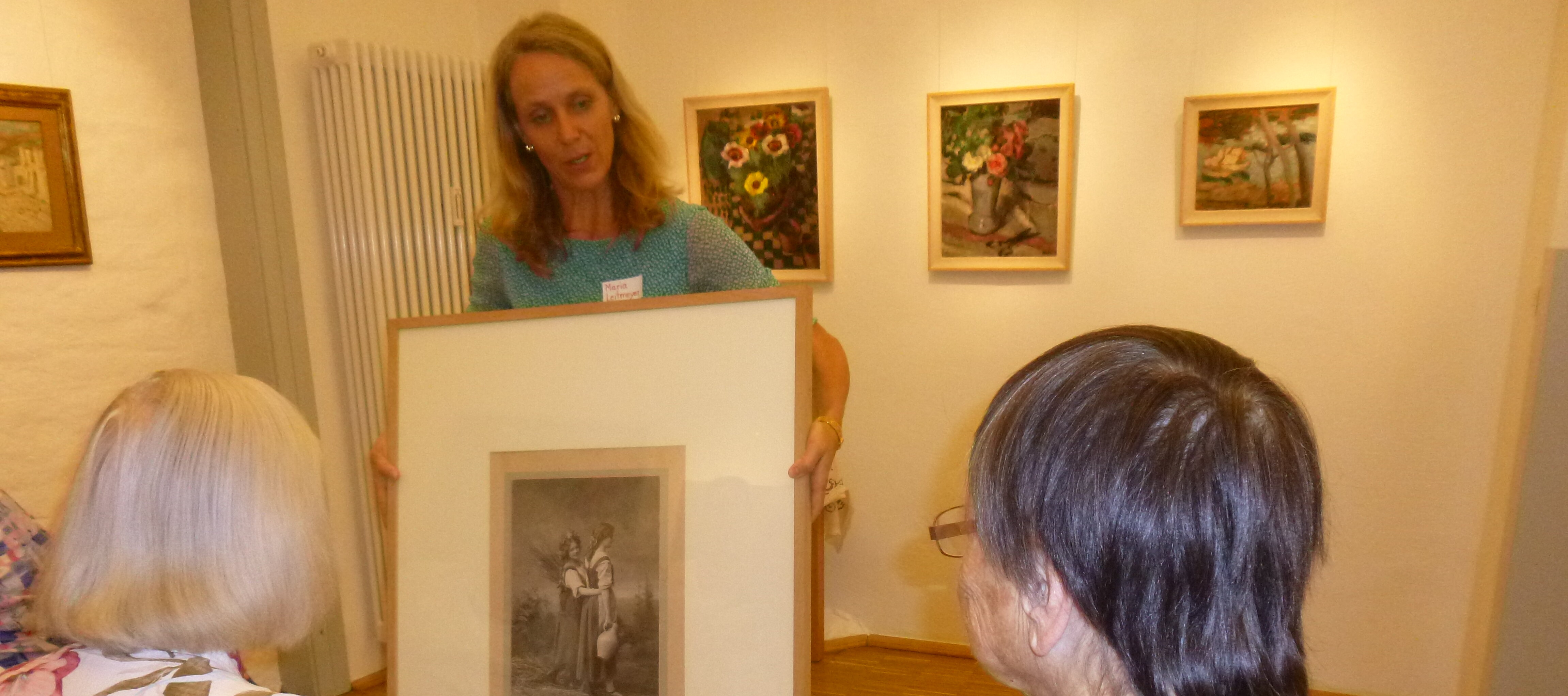 Foto: Eine Frau zeigt zwei älteren Damen ein Kunstwerk