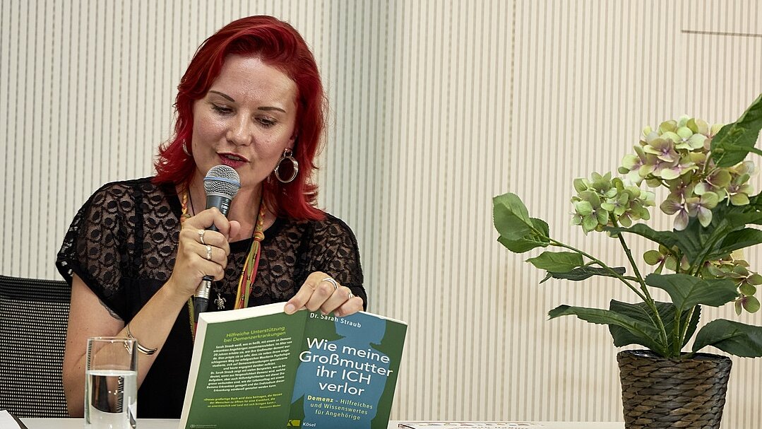 Foto: Sarah Straub mit Mikrofon und Buch in der Hand