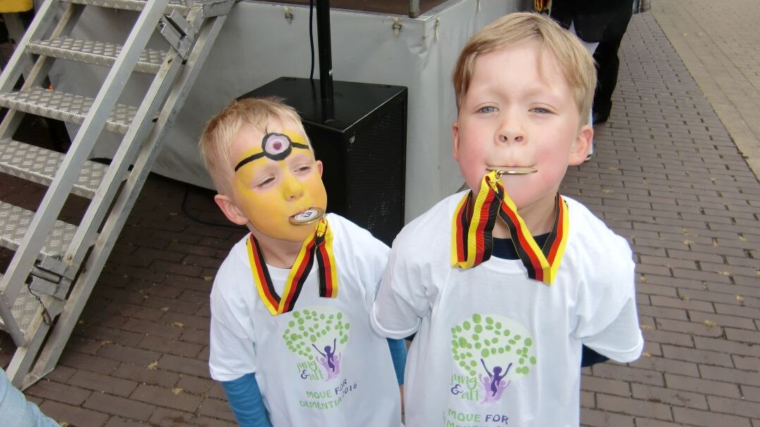 Auf diesem Foto stehen zwei kleine Jungs mit einer Medaille um den Hals