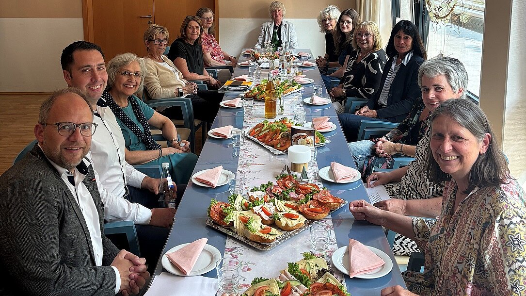 Foto: Eine Gruppe Menschen sitz an einem gedeckten Tisch