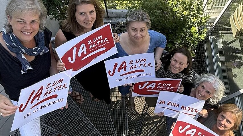 Foto: Mitarbeiterinnen zeigen ein Schild "Ja zum Alter"