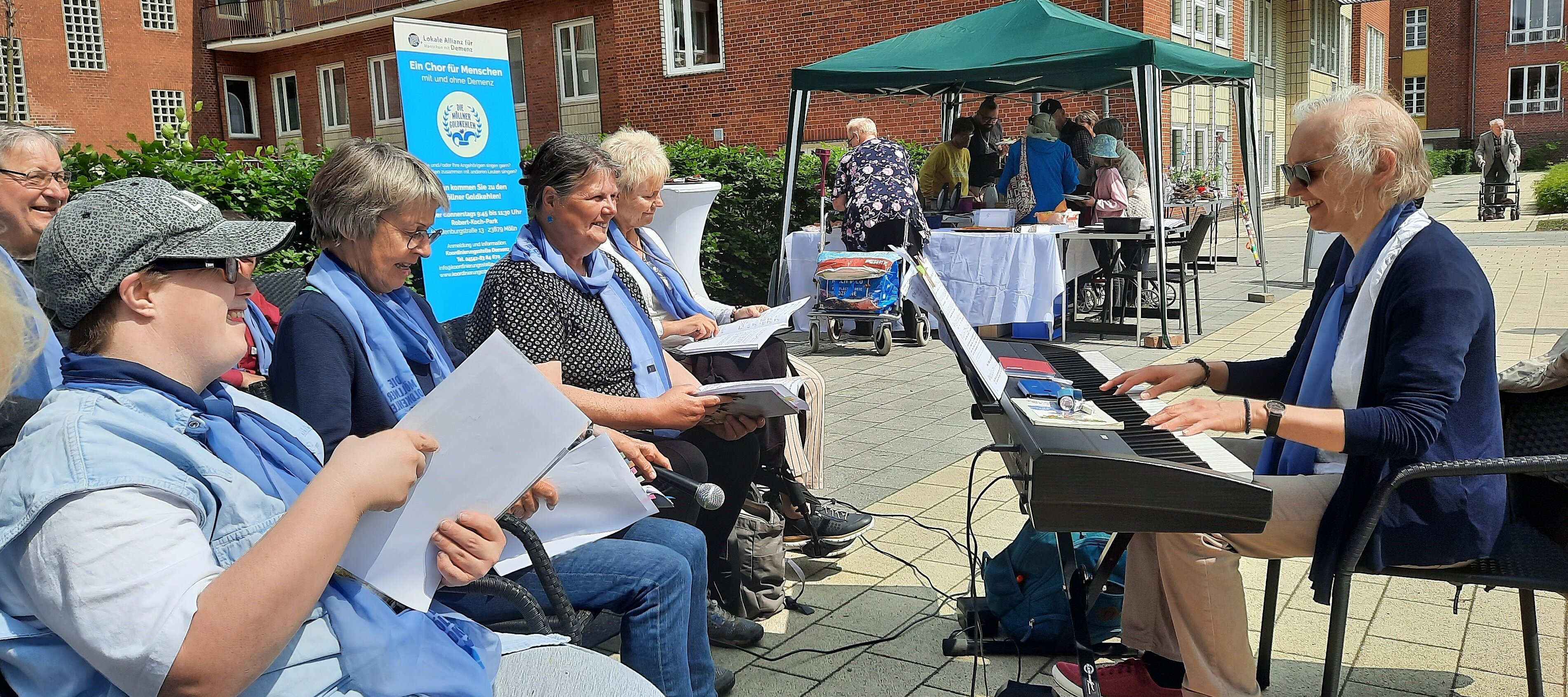 Foto: Eine Frau an einem Keyboard und singende Teilnehmer der Möllner Goldkehlen