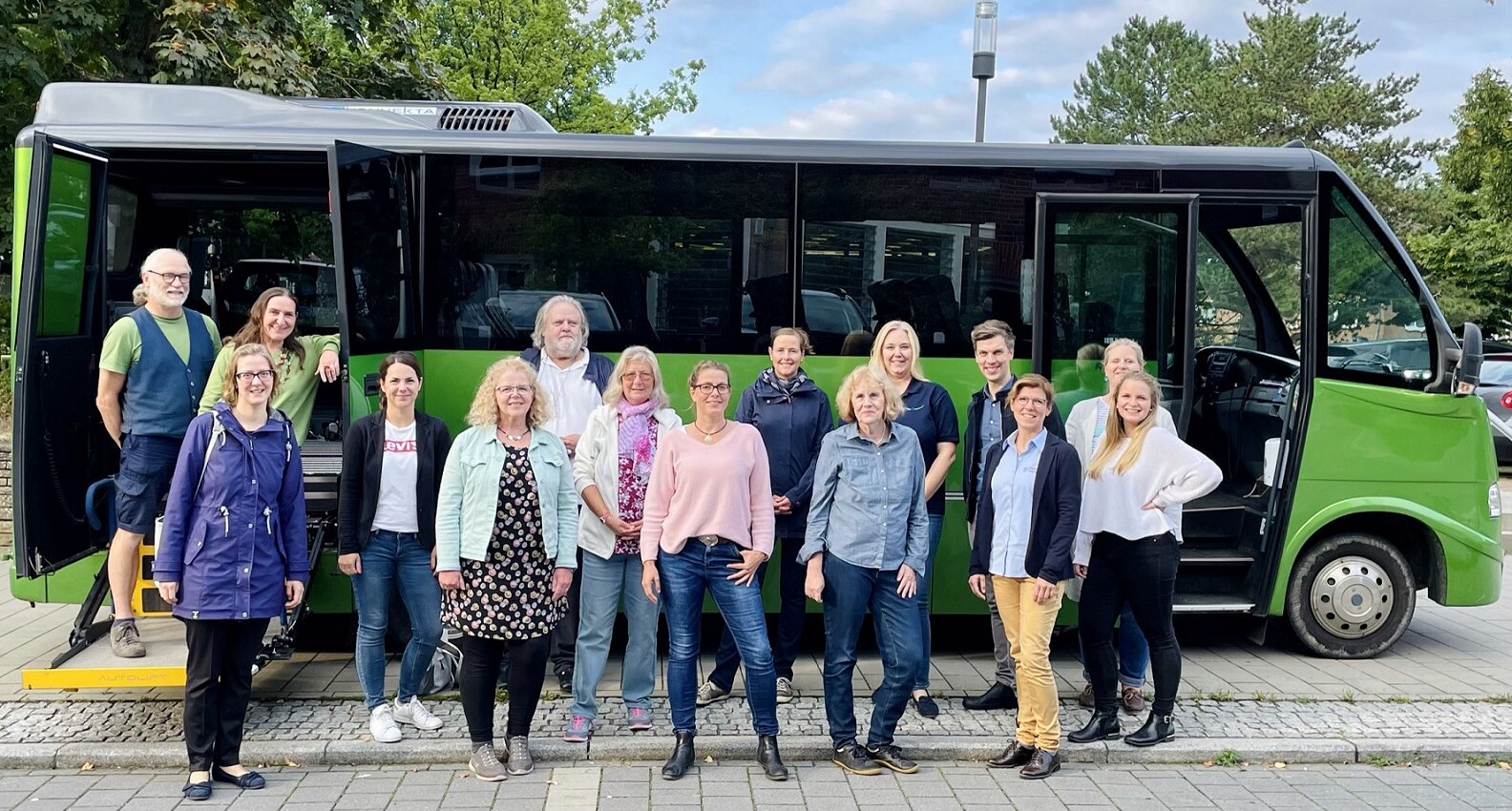 Gruppenfoto mit 15 Männern und Frauen aus der Lokalen Allianz vor dem grünen Bus