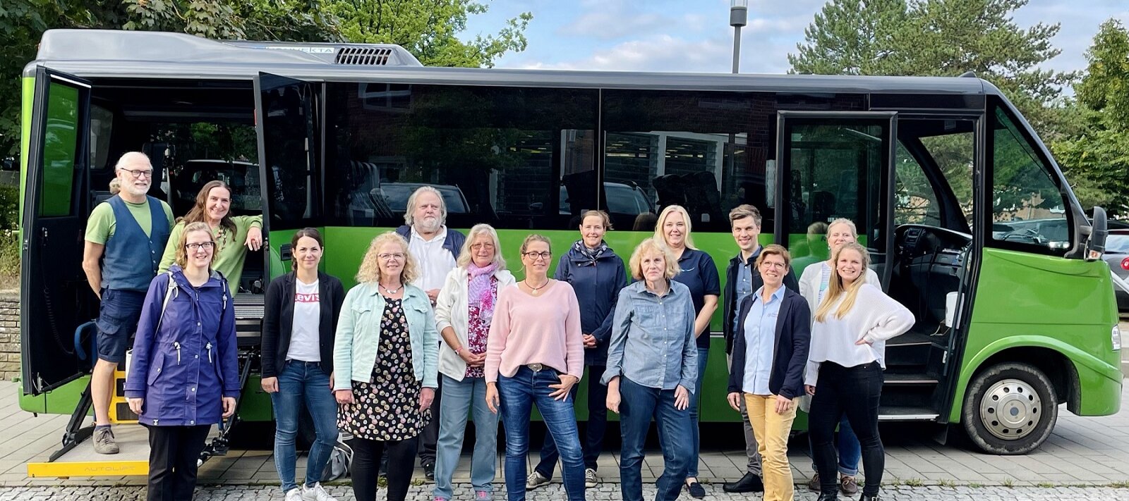 Gruppenfoto mit 15 Männern und Frauen aus der Lokalen Allianz vor dem grünen Bus