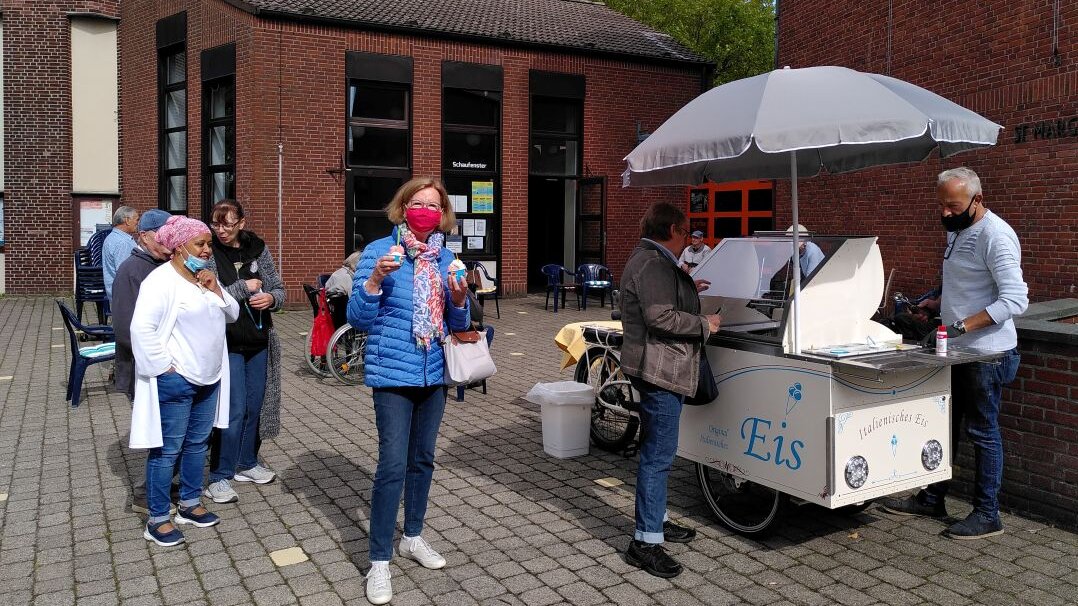 Foto: Ein kleiner Eiswagen und Menschen, die für ein Eis anstehen.
