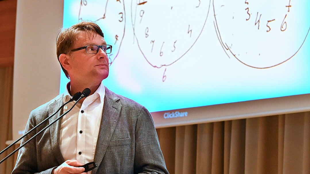 Vortrag von Prof. Dr. Thomas Duning, Chefarzt der Klinik für Neurologie, Klinikum Bremen-Ost | „Demenz-Info-Tag“, Oktober 2024 in Stuhr Foto: Prof. Dr. Thomas Duning steht an Rednerpult vor großer Leinwand