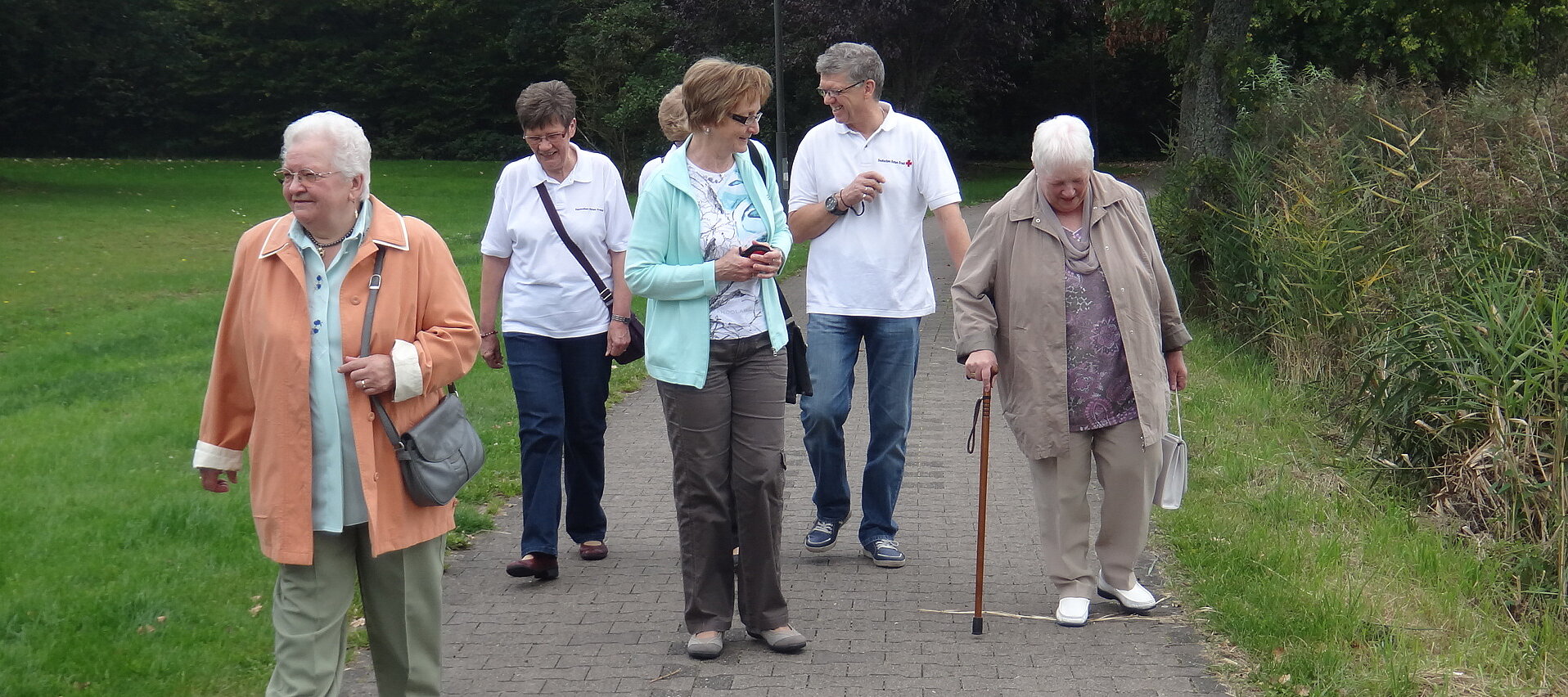 Foto: Die Dorfschwester Annetraud Kling geht mit einer Gruppe älterer Menschen im Park spazieren.