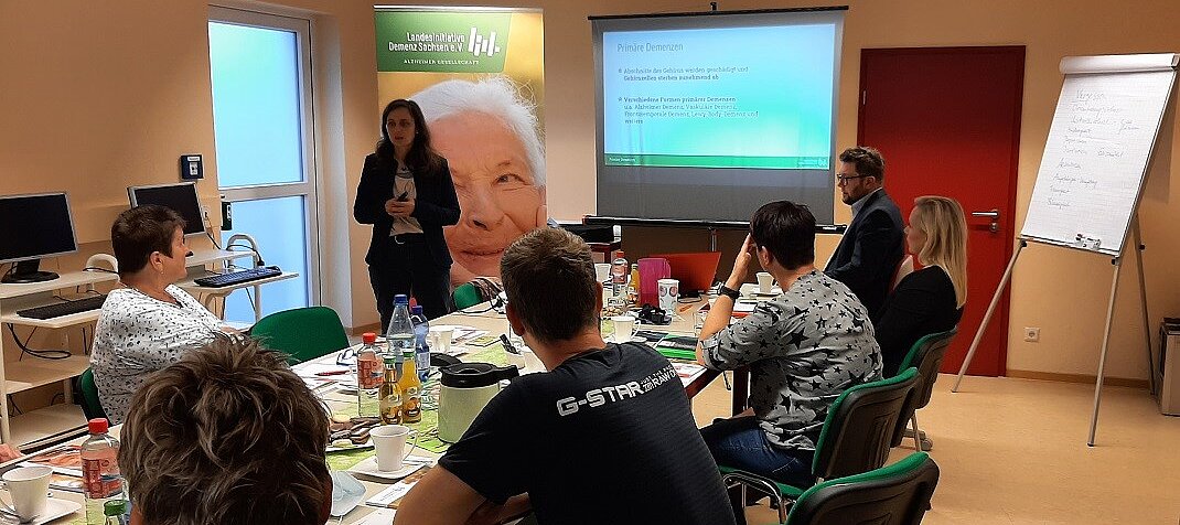 Foto: Personengruppe bei einer Präsentation mit Vortrag.