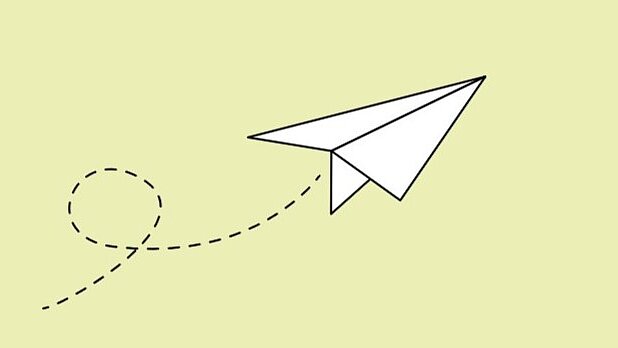 Weißer Papierflieger auf hellgrünem Hintergrund