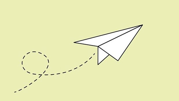 Weißer Papierflieger auf hellgrünem Hintergrund