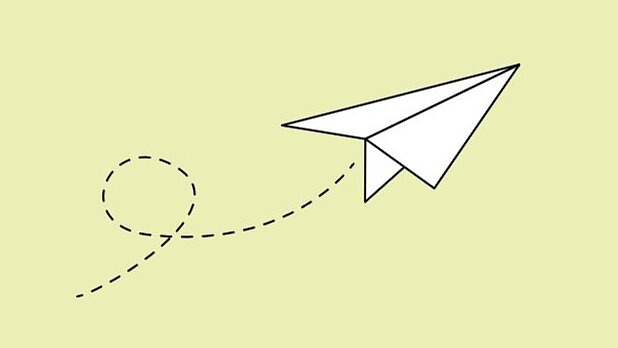 Weißer Papierflieger auf hellgrünem Hintergrund